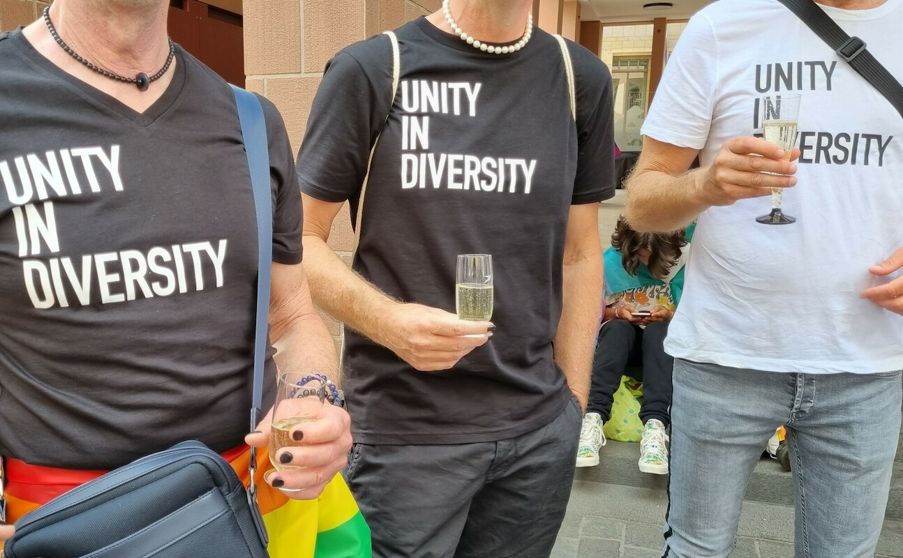Man sieht drei Männer mit T-Shirts mit dem Aufdruck Unity in Diversity